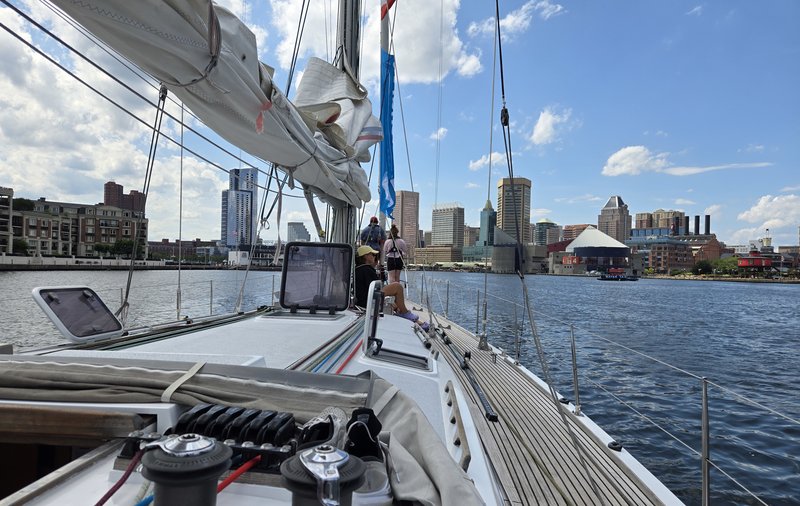 Blick vom Segelschiff aus auf städtische Skyline mit heruntergelassenem Segel