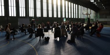 Schmuckbild - Menschen sitzen im Gegenlicht in einer Halle
